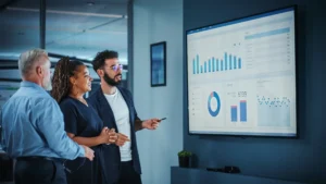 Three IT professionals working together in front of a large dashboard screen